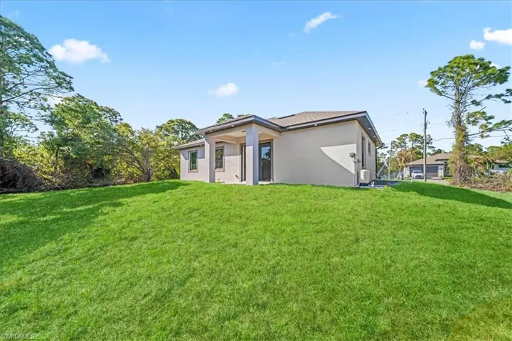Rear view of property with a yard and stucco siding