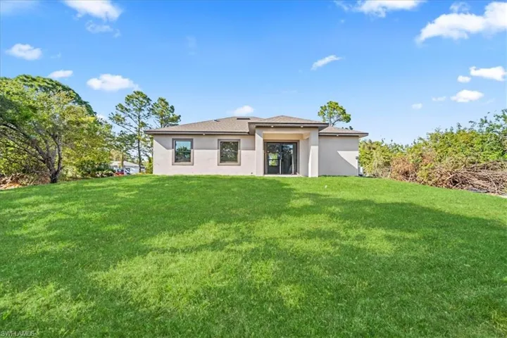 Rear view of house featuring stucco siding and a lawn