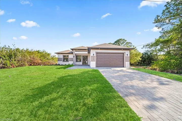 Prairie-style home featuring an attached garage, driveway, stucco siding, and a front yard