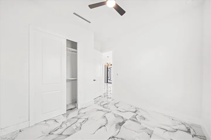 Unfurnished bedroom featuring a ceiling fan, a closet, and light marble finish flooring
