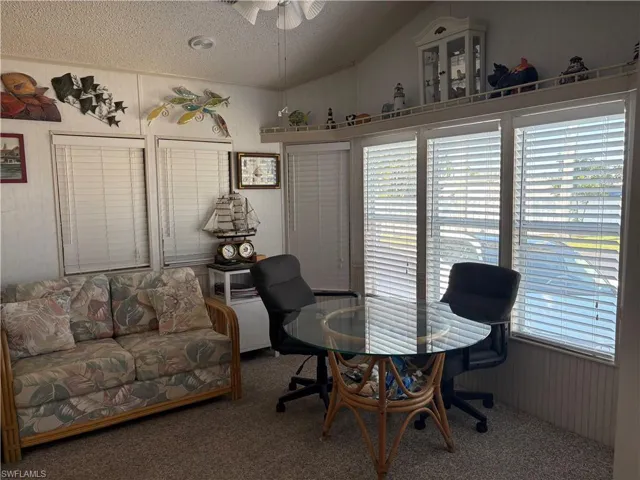 Eat in kitchen with ceiling, wood walls, vaulted ceiling, and a ceiling fan