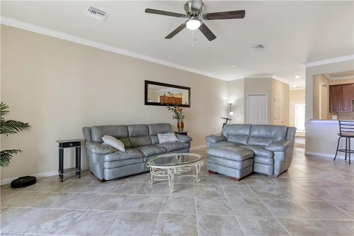 Living area featuring ornamental molding, light tile patterned floors, and a ceiling fan