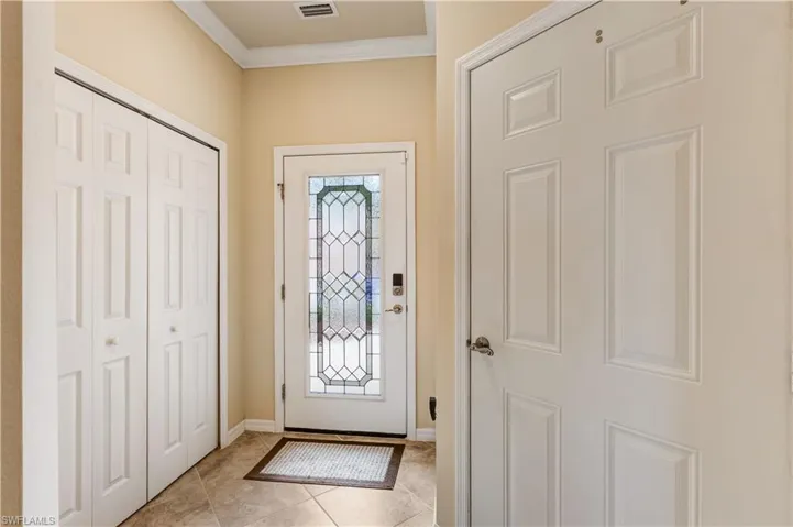 Foyer featuring crown molding and light tile patterned flooring