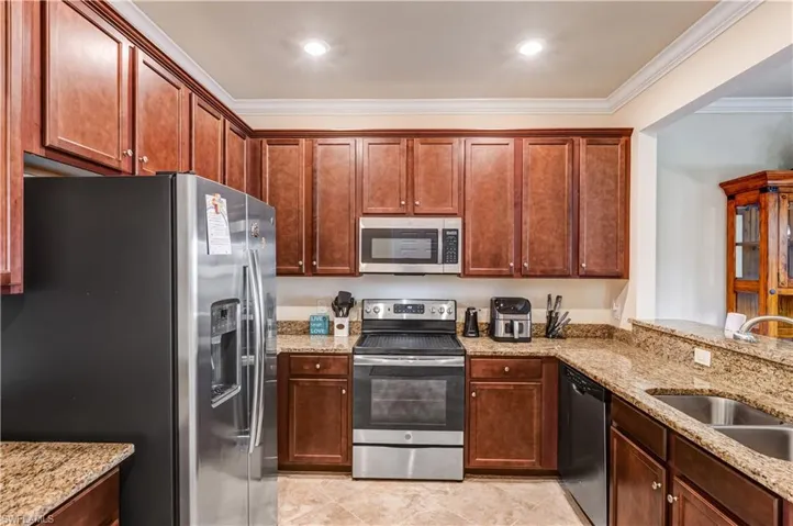 Kitchen with stainless steel appliances, light stone countertops, crown molding, light tile patterned floors, and recessed lighting