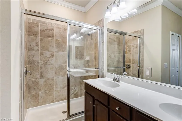 Bathroom featuring a stall shower, double vanity, and ornamental molding