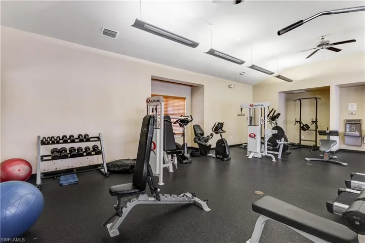 Exercise room featuring a ceiling fan and baseboards