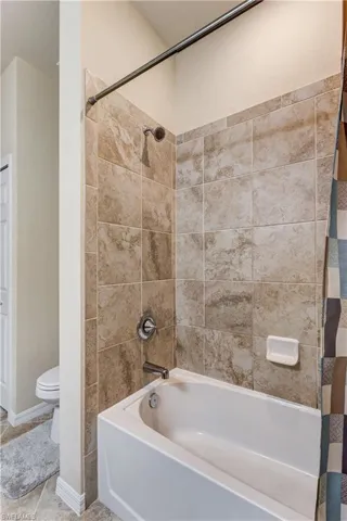 Full bath with shower / bath combo with shower curtain and tile patterned floors