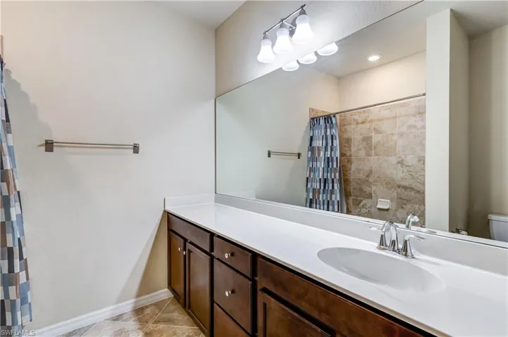 Bathroom featuring vanity, light tile patterned floors, and a shower with shower curtain