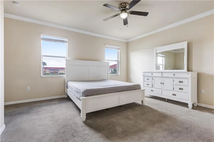 Carpeted bedroom with crown molding and ceiling fan