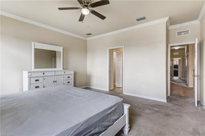 Carpeted bedroom featuring crown molding and ceiling fan