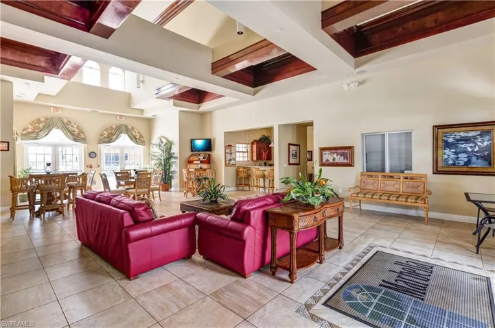 Kitchen featuring stainless steel fridge with ice dispenser, brown cabinets, light stone counters, and light tile patterned flooring