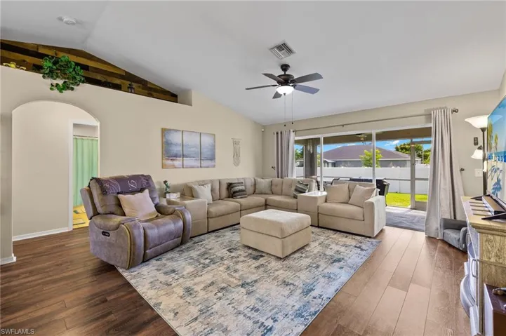Living room featuring wood-type flooring, ceiling fan, and vaulted ceiling