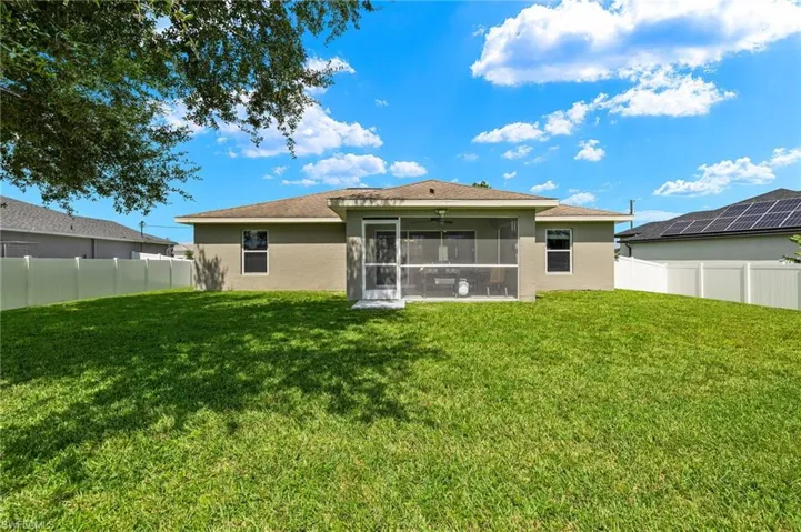 Rear view of property with a lawn and a sunroom