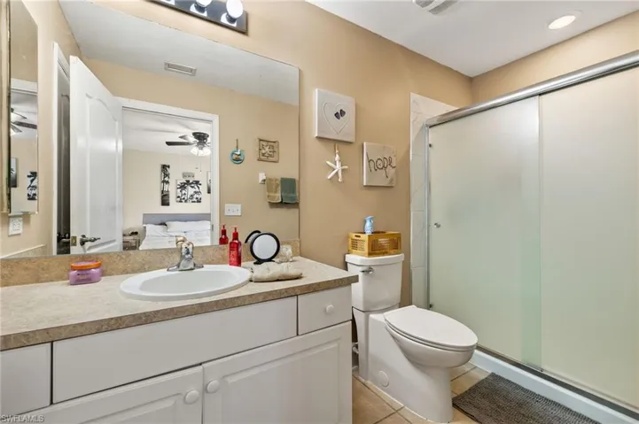 Bathroom with vanity, ceiling fan, walk in shower, toilet, and tile patterned flooring