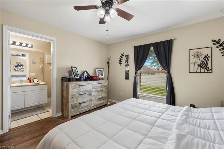 Bedroom featuring hardwood / wood-style flooring, ensuite bathroom, sink, and ceiling fan