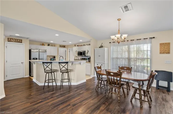 Dining room featuring sink, a chandelier, dark hardwood / wood-style flooring, and vaulted ceiling