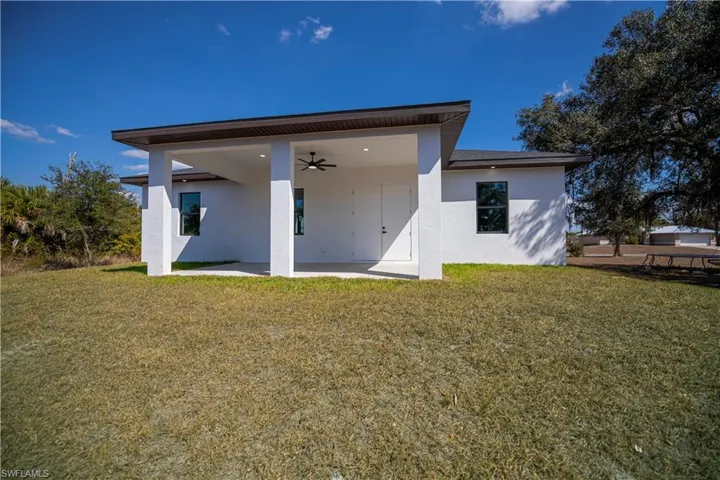 Back of property featuring a ceiling fan, stucco siding, a yard, and a patio area