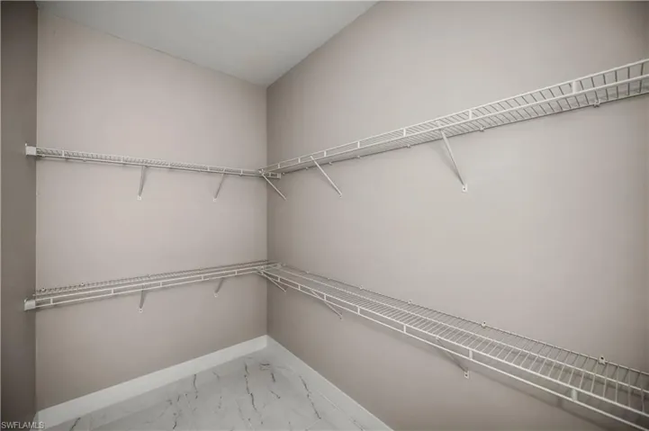 Walk in closet with light marble finish flooring