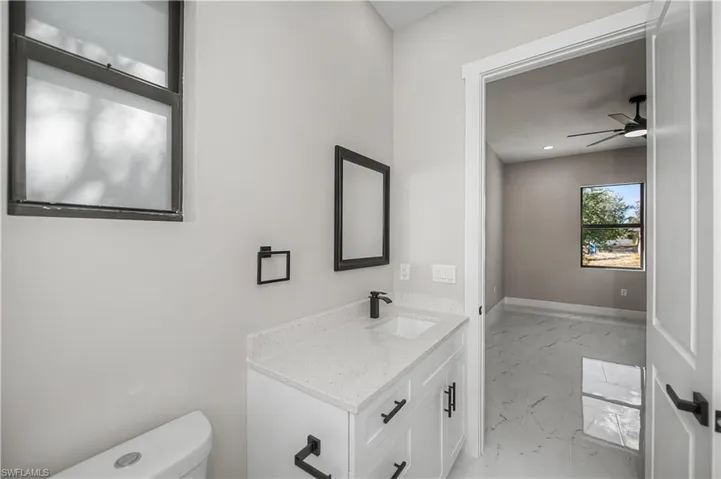 Bathroom with a ceiling fan, light marble finish flooring, and vanity