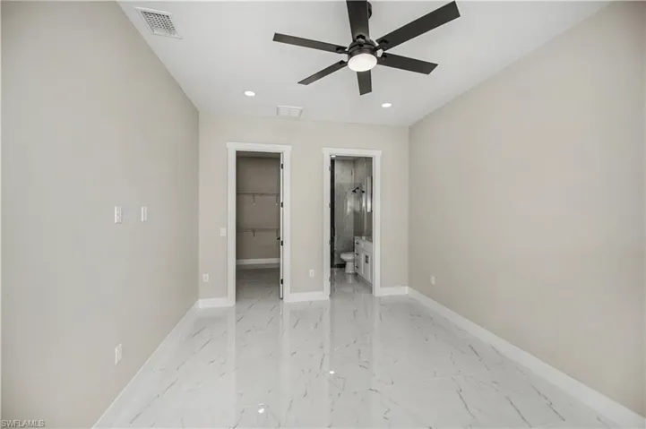 Unfurnished bedroom featuring a walk in closet, light marble finish flooring, recessed lighting, and ceiling fan