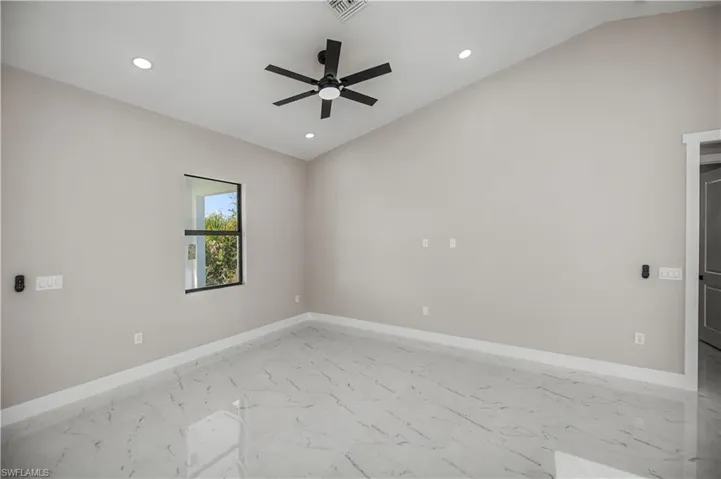 Spare room featuring lofted ceiling, marble look tile flooring, a ceiling fan, and recessed lighting