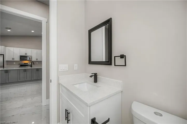 Bathroom featuring vanity, light marble finish floors, and recessed lighting