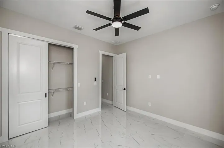 Unfurnished bedroom with light marble finish flooring, a ceiling fan, and a closet