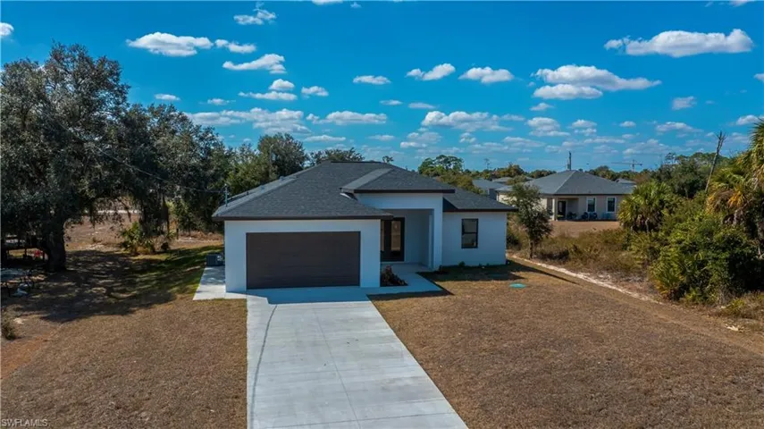 View of front of property with concrete driveway, stucco siding, roof with shingles, and an attached garage