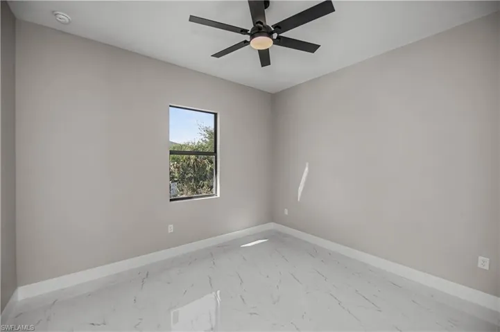 Empty room with marble look tiles and a ceiling fan