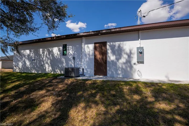 Back of property featuring a lawn and stucco siding