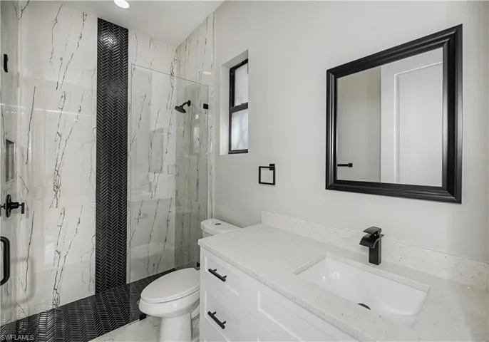 Bathroom with a marble finish shower and vanity