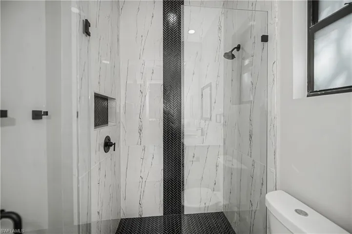 Full bath with a marble finish shower