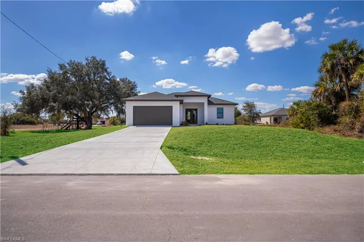 Prairie-style home featuring a front lawn, concrete driveway, stucco siding, and a garage