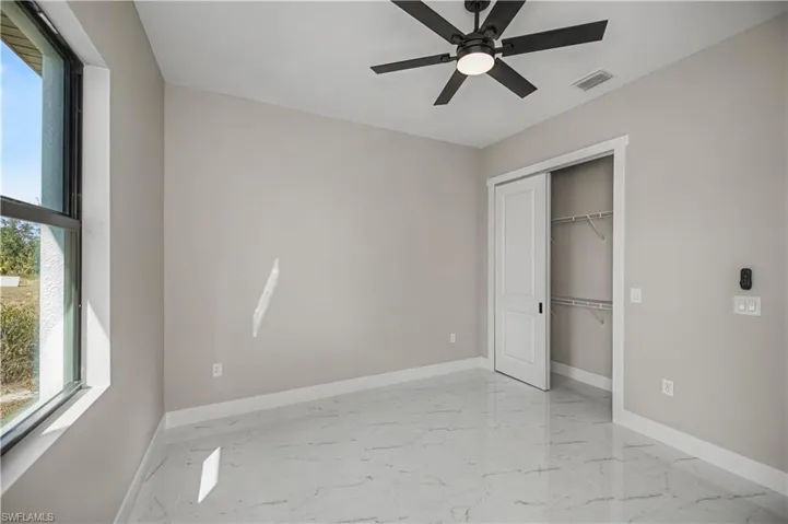Unfurnished bedroom with a closet, a ceiling fan, and light marble finish floors