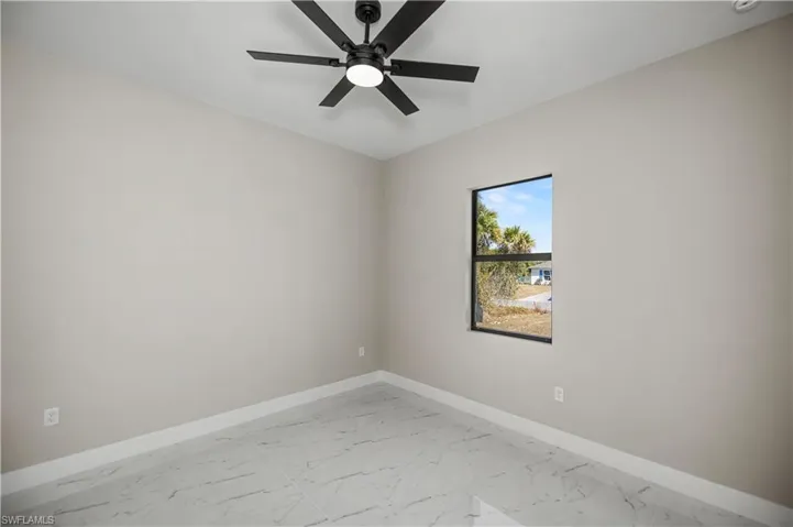 Spare room with light marble finish floors and a ceiling fan