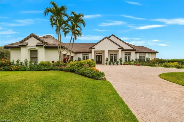 View of front of home featuring decorative driveway, stucco siding, a front yard, and a tiled roof