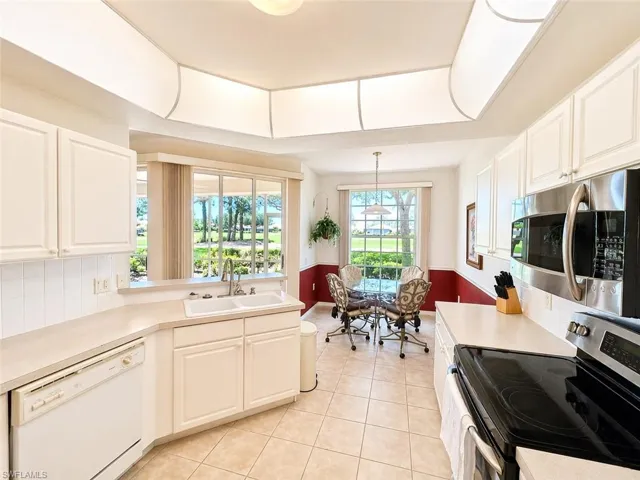 Well-maintained kitchen with ample cabinetry, solid surface counters, and breakfast bar.