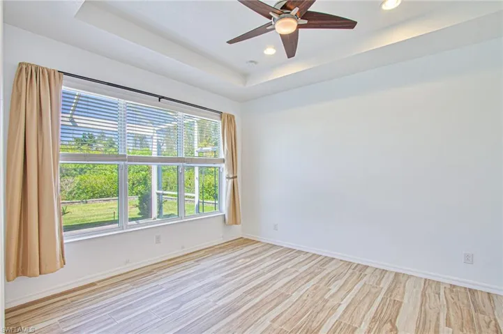 Primary Bedroom with tile flooring, view to backyard; tray ceiling