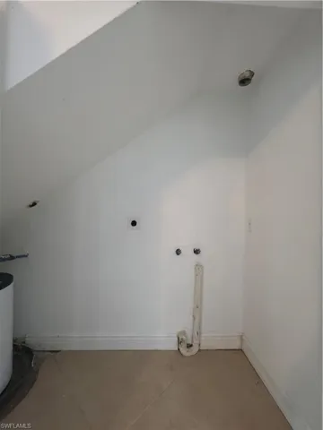 Under-stair alcove featuring neutral tile flooring and dedicated utility hookups