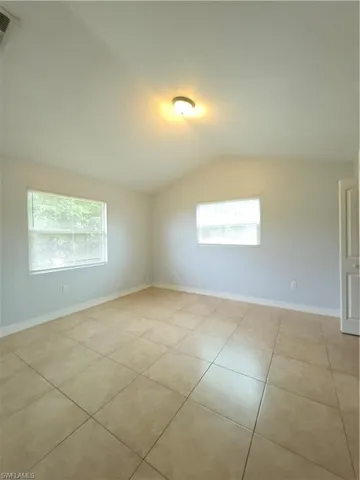 Vaulted ceiling, neutral wall tones, large-format tile flooring, and dual windows providing natural light