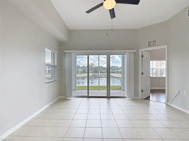 Unfurnished room with a ceiling fan, a water view, and light tile patterned floors