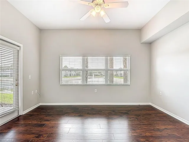Empty room with a ceiling fan and dark wood finished floors