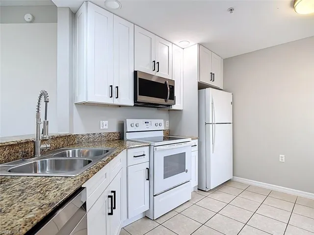 Kitchen featuring stainless steel appliances, white cabinets, and light tile patterned floors