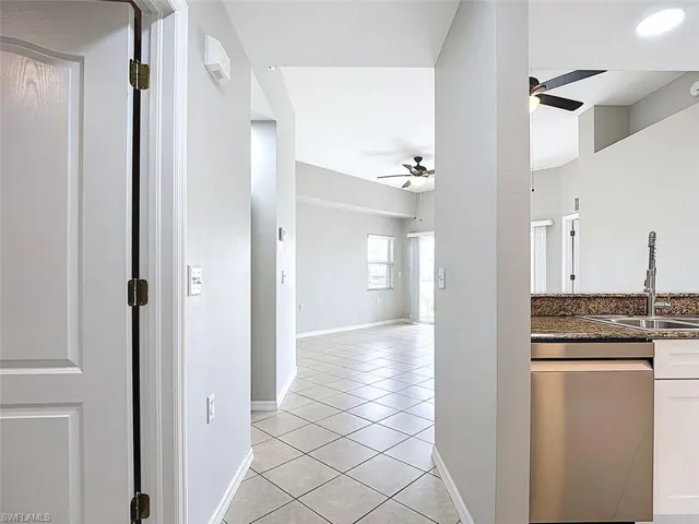 Kitchen featuring dishwasher, a ceiling fan, dark stone counters, and light tile patterned floors