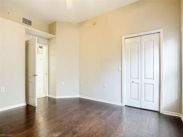 Unfurnished bedroom featuring dark wood-type flooring and ceiling fan
