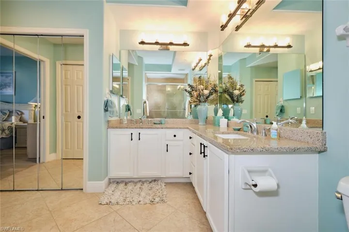 Bathroom with tile patterned floors, vanity, toilet, and a shower with door