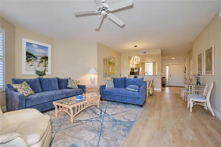 Living room featuring ceiling fan with notable chandelier and light wood-type flooring