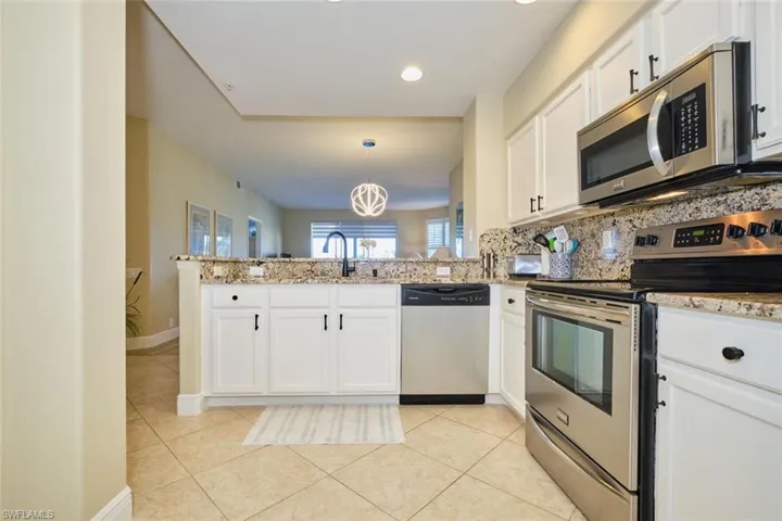 Kitchen featuring white cabinets, kitchen peninsula, stainless steel appliances, and hanging light fixtures