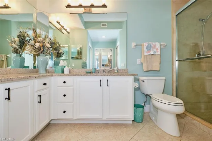 Bathroom featuring vanity, a shower with door, tile patterned flooring, and toilet