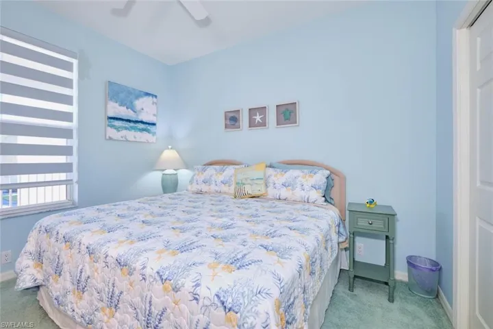 Bedroom with ceiling fan, light colored carpet, and a closet